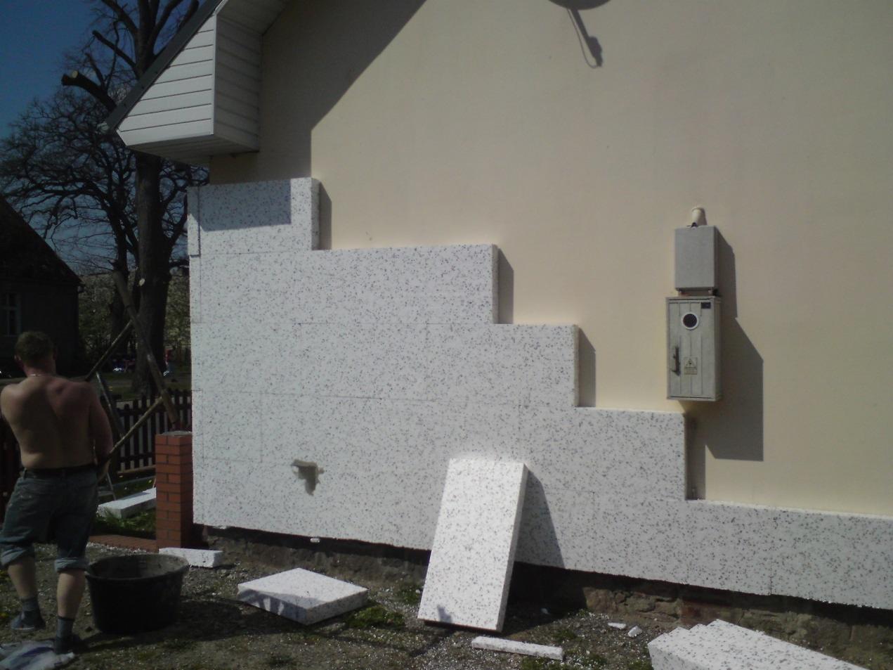 Ocieplanie ściany budynku styropianem w Dolicach. Fragment fasady z widocznym etapem montażu izolacji termicznej. Prace remontowe w toku.