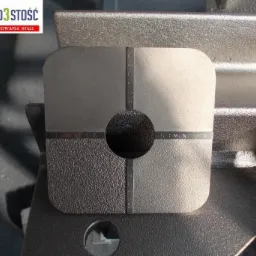 Metalowy element testowy z różnymi powierzchniami i oznaczeniami, ukazujący efekty obróbki śrutowania w czterech segmentach.