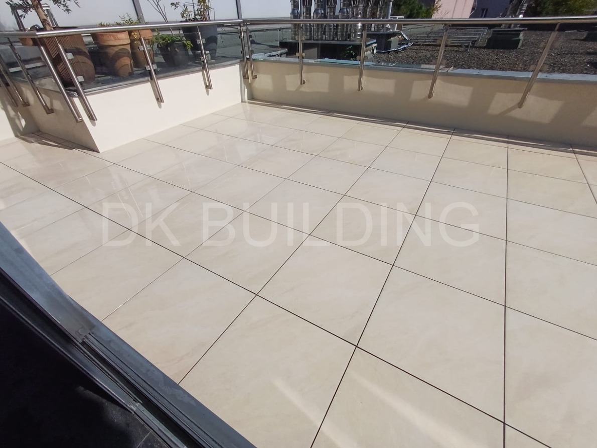 Jasne, kwadratowe płytki na balkonie z metalową balustradą i donicami. Widok z góry, delikatne oświetlenie.