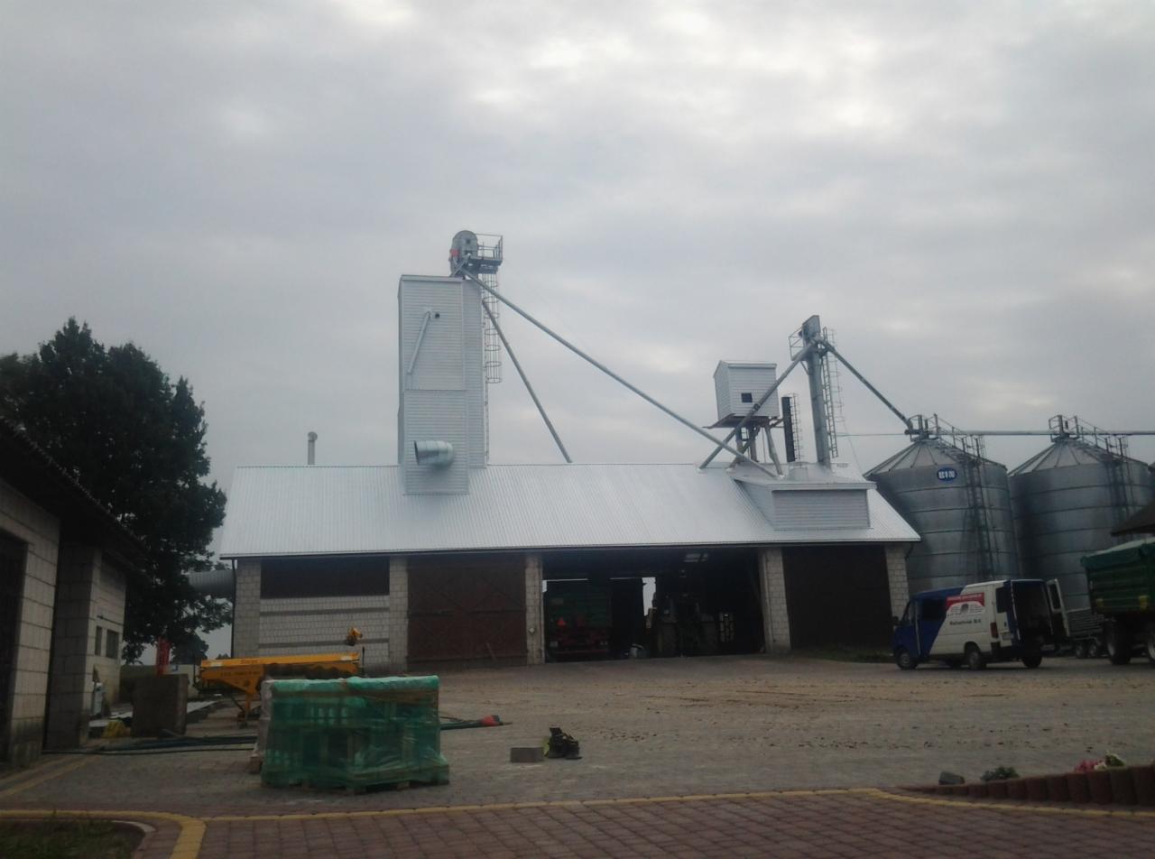 Metalowy dach z konstrukcją silosów na budynku gospodarczym, widok z zewnątrz w pochmurny dzień. Jasna blacha trapezowa na dachu.