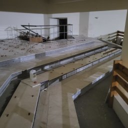 OL-BAU ŁUKASZ WĄWOŹNY - Wnętrze w trakcie prac wykończeniowych: ułożone płytki na schodach, widoczne narzędzia i materiały budowlane. Etap prac przed finalnym wykończeniem.