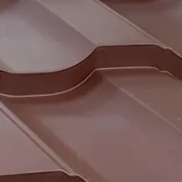 Szczegółowe ujęcie brązowej blachy dachowej z wyraźnym wzorem tłoczenia i widocznymi łączeniami, ukazujące fakturę i kształt materiału.