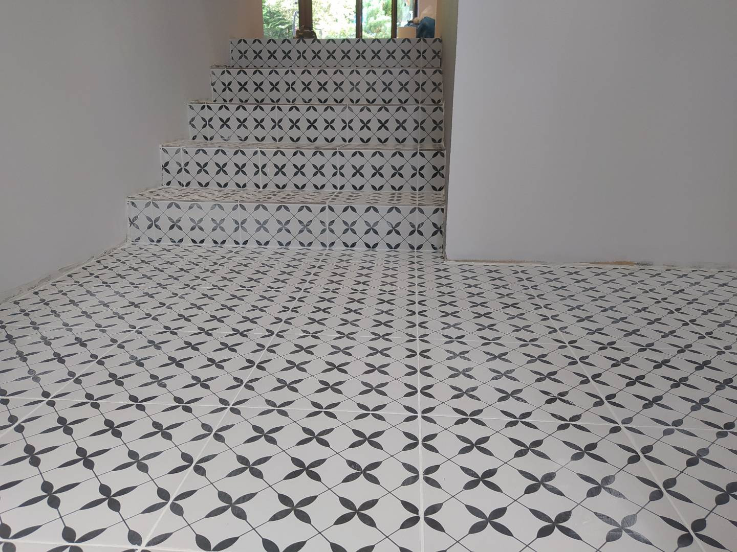Ułożona podłoga i schody w biało-czarne wzory geometryczne, widok z dołu, ściany pomalowane na szaro.
