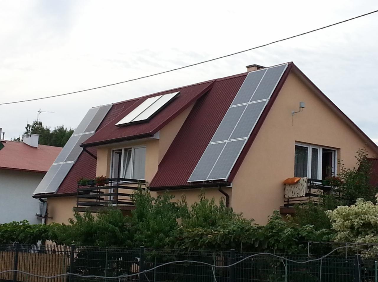 Instalacja fotowoltaiczna na dachu dwuspadowym domu jednorodzinnego w Tarnobrzegu, widok z poziomu ulicy na panele zamontowane na różnych połaciach dachu.