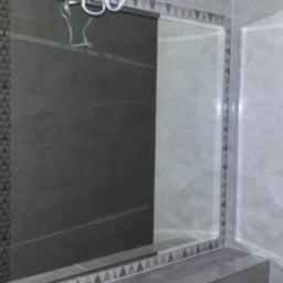 PRZEDSIĘBIORSTWO USŁUGOWO - HANDLOWE SAN-MARC FILIP MARCHELA - Wykończona łazienka z szarymi płytkami, dekoracyjnym wzorem trójkątów i grzejnikiem drabinkowym. Widoczne detale wykończenia i oświetlenie.