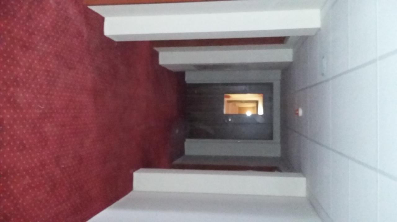 Wnętrze korytarza z czerwonym dywanem na ścianie i białymi elementami architektonicznymi, widok z góry, perspektywa zbieżna w stronę okna.