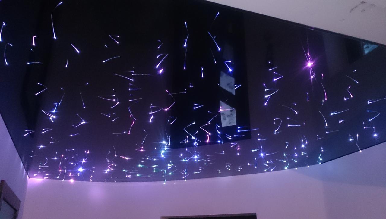 Błyszczący sufit napinany z efektem gwiaździstego nieba w odcieniach fioletu i błękitu, widok z dołu na fragment wnętrza.