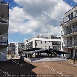 P.P.H.U. WAWMAR MAREK WAWRZONOWSKI - Nowoczesne osiedle z widoczną siatką ogradzającą teren, w tle zadaszona konstrukcja, błękitne niebo z chmurami.