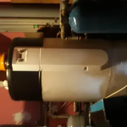 Nowoczesny piec gazowy z podłączonymi przewodami wentylacyjnymi i elementami instalacji, widoczny w pomieszczeniu o różowych ścianach.