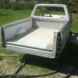 Wnętrze paki pickupa po obróbce, widoczne ślady po czyszczeniu i przygotowaniu do dalszych prac. Jasny kolor, tło to trawa i zabudowania.