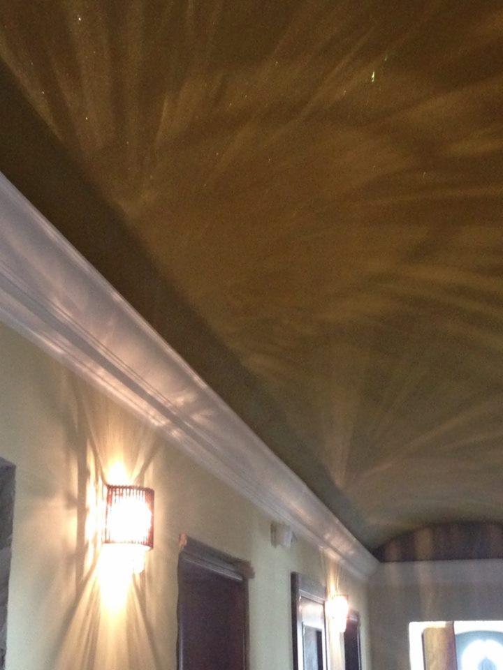 Wnętrze z dekoracyjnym, brązowym sufitem z efektem rozgwieżdżonego nieba, podkreślonym przez listwy przysufitowe i oświetlenie ścienne.