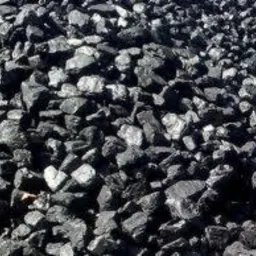 Błyszcząca sterta czarnego węgla kamiennego w zbliżeniu, z widocznymi nieregularnymi kształtami brył i odbiciami światła na ich powierzchni.