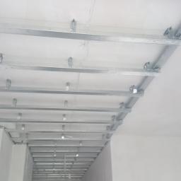 EKO-INSTAL PIOTR BAJOR - Metalowy stelaż sufitowy z widocznymi przewodami elektrycznymi, zamontowany w pomieszczeniu przed położeniem płyt gipsowo-kartonowych.