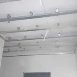 Stelaż sufitowy z płyt karton-gips, widoczne profile metalowe, uchwyty montażowe i przewody instalacji elektrycznej, przygotowany do montażu płyt.