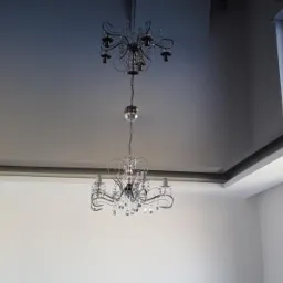 Błyszczący, szary sufit z dwiema kryształowymi lampami, widok z dołu, jasne wnętrze z oknami.