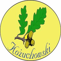 Grafika w okręgu: zielone liście dębu i żołędzie nad napisem 'Kożuchowski' w kursywie, na żółtym tle z czarną obwódką. Element identyfikacji wizualnej.