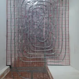 Montaż szarego systemu rur na izolacji pod ogrzewanie podłogowe w Strzelcach Opolskich, widok z góry na przygotowaną powierzchnię.