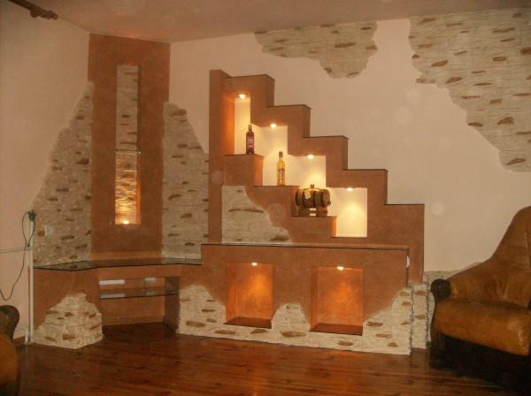 Stylowa aranżacja wnętrza z półkami schodkowymi, dekoracyjnym kamieniem i podświetleniem, tworząca unikatowy element wystroju.