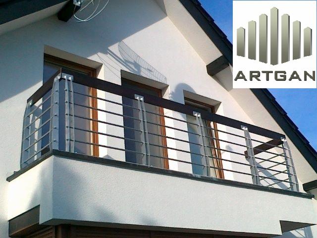 Nowoczesna balustrada balkonowa z metalowymi prętami i drewnianym wykończeniem, zamontowana na białej fasadzie budynku z widocznymi oknami.