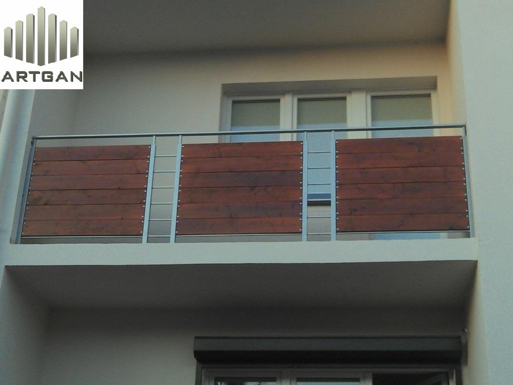 Nowoczesna balustrada balkonowa z drewnianymi panelami i metalowymi słupkami, widok z dołu, jasna elewacja budynku.