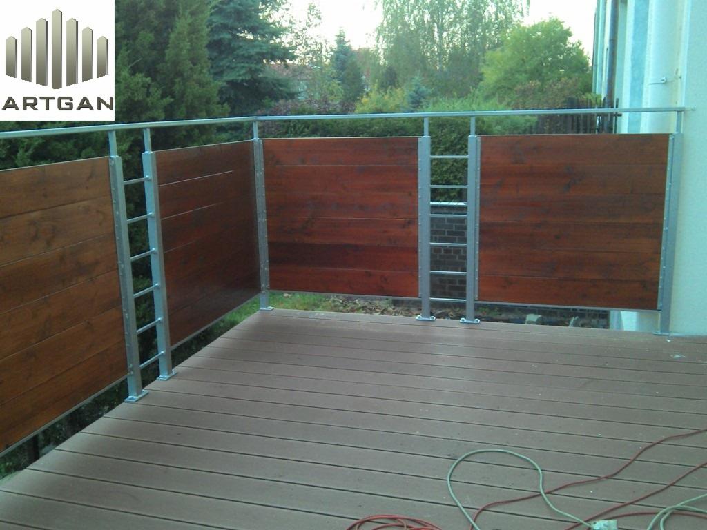 Nowoczesne ogrodzenie balkonowe z brązowych desek i metalowych słupków, widok z bliska na drewnianą podłogę i zielone otoczenie.