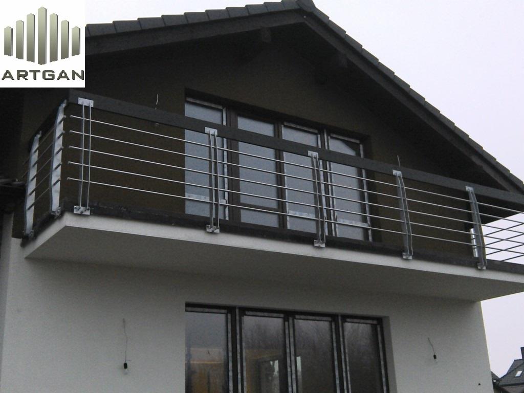 Nowoczesna balustrada balkonowa ze stali nierdzewnej, z poziomymi prętami i ciemnym drewnianym wykończeniem, na tle dwupiętrowego domu z oknami.