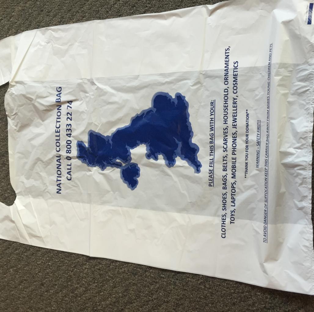 Biała torba na zbiórkę odzieży z nadrukowanym konturem mapy i listą akceptowanych przedmiotów: ubrania, buty, zabawki, elektronika. Numer telefonu do kontaktu.