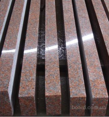 Rzędy ciętych, czerwono-brązowych elementów z granitu, ułożonych równolegle, tworzących regularny wzór z widocznymi krawędziami i fakturą kamienia.