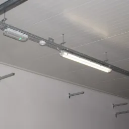 Zamontowane oświetlenie przemysłowe LED na szynoprzewodach w hali w Szydłowcu, widoczny także czujnik dymu i lampa awaryjna.