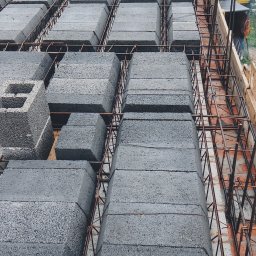 F.H.U. Ciapka Rafał Usługi Budowlane - Strop żebrowy z szalunkiem i zbrojeniem, widok z góry. Szare bloczki ułożone w rzędach, pomiędzy nimi zbrojenie. Widoczne elementy drewnianego szalunku.