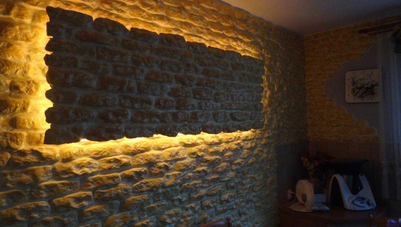 Dekoracyjna ściana z kamienia z podświetleniem LED, tworząca ciepłą atmosferę. Fragment ściany o nieregularnym kształcie podświetlony od tyłu.