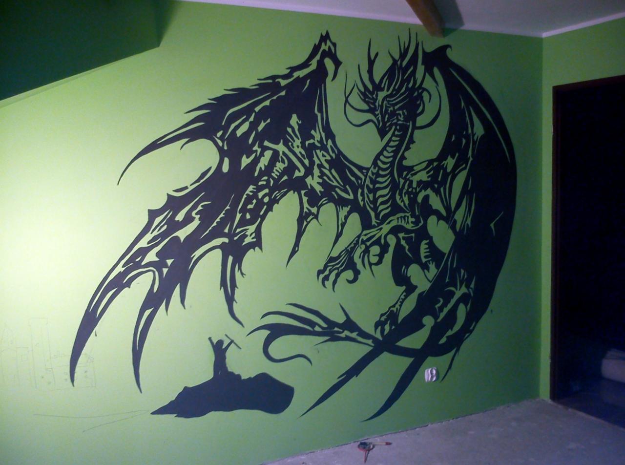 Czarny rysunek smoka i sylwetki człowieka na zielonej ścianie. Rysunek wykonany bezpośrednio na ścianie, widoczne niedokończone elementy.