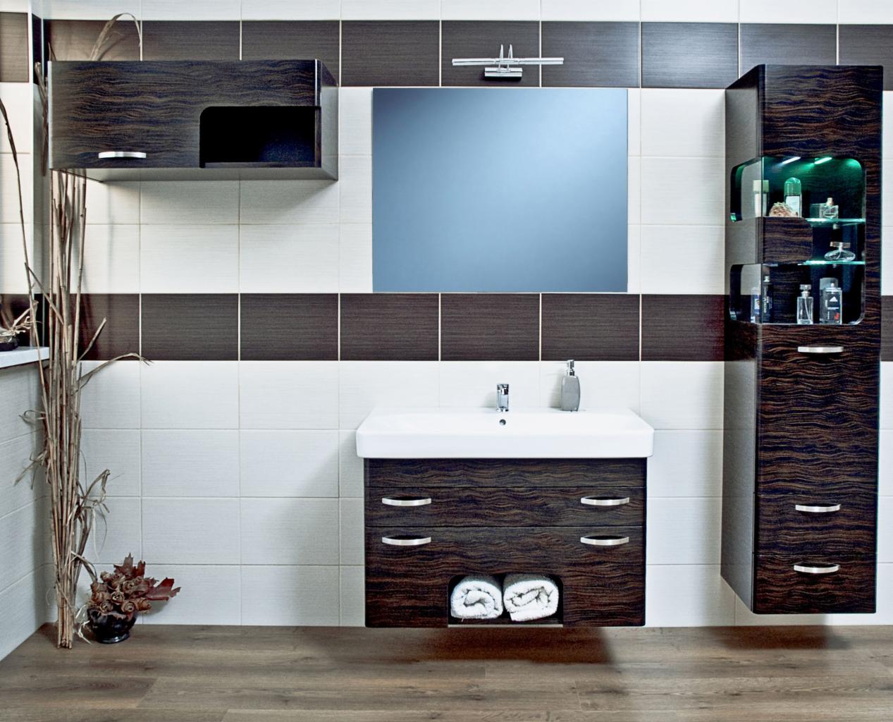 Nowoczesna łazienka z szafkami z ciemnego drewna o unikalnym wzorze, białą umywalką i lustrem. Dekoracyjne akcenty: wysokie, suche trawy w wazonie.