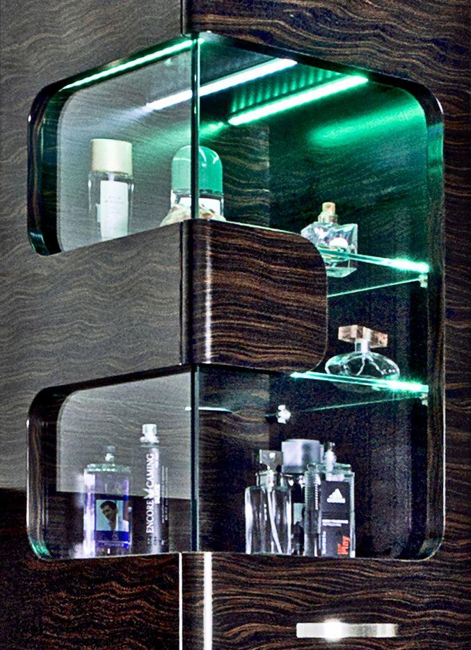 Nowoczesna szafka z podświetleniem LED i szklanymi półkami, Praszka. Wykończenie w ciemnym drewnie ze wzorem, eksponuje flakony perfum i kosmetyków.