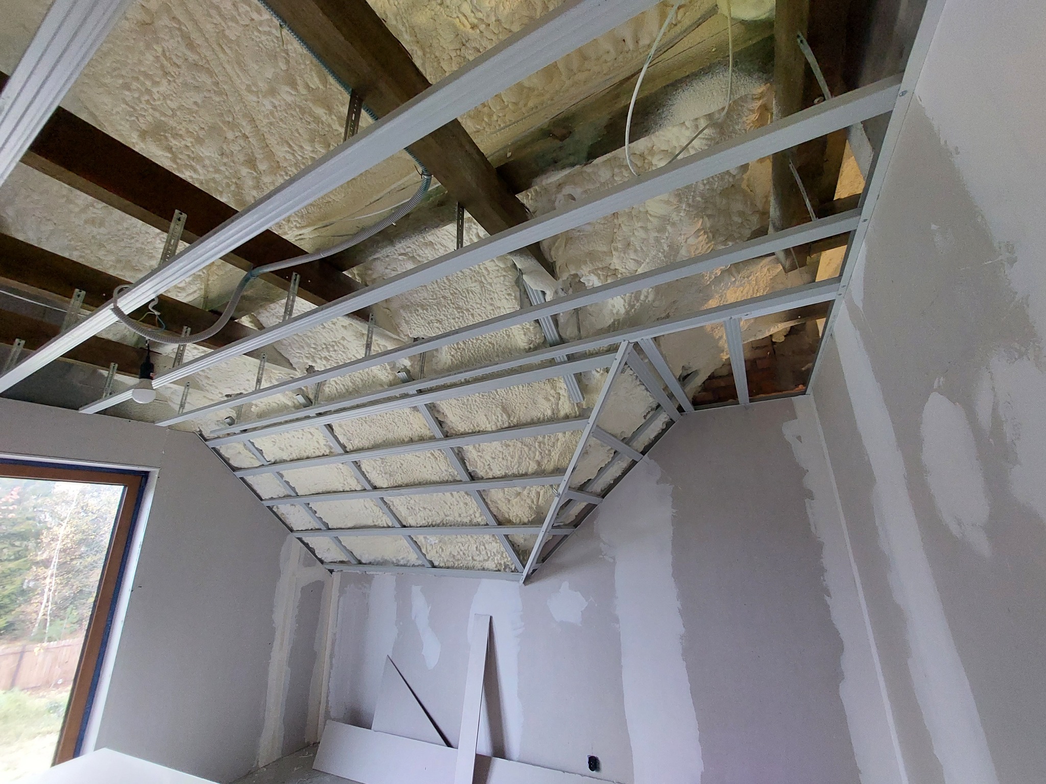 Sufit podwieszany z metalową konstrukcją, ocieplony pianą, ściany w trakcie szpachlowania, widoczne płyty gipsowo-kartonowe.