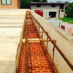 Zbrojenie wieńca na murze z czerwonej cegły dziurawki, szalunek z desek, budynek w stanie surowym otwartym, widok z g&oacute;ry.