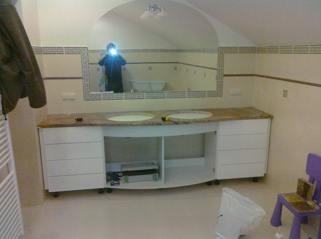 Wykończona łazienka z umywalkami nablatowymi na szafce z blatem imitującym marmur. W tle lustro i płytki. Widoczna osoba robiąca zdjęcie w lustrze.