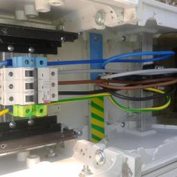 Instalacje-techniczne.pl - Szczegółowe ujęcie wnętrza skrzynki elektrycznej z bezpiecznikami i przewodami w Świdnicy. Widoczne złącza, kable w różnych kolorach i elementy montażowe.