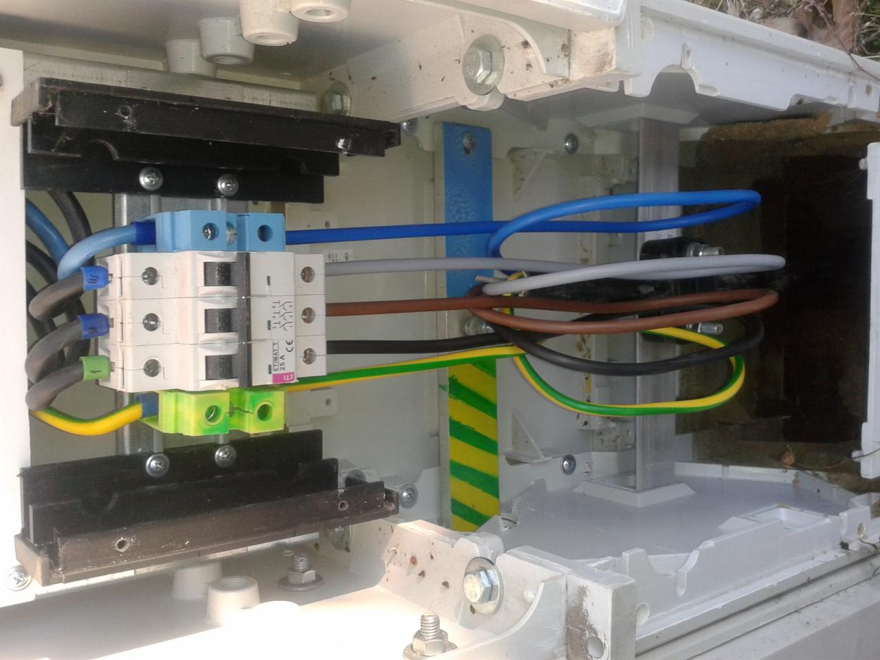 Szczegółowe ujęcie wnętrza skrzynki elektrycznej z bezpiecznikami i przewodami w Świdnicy. Widoczne złącza, kable w różnych kolorach i elementy montażowe.