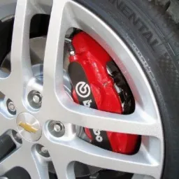 Felga aluminiowa Chevrolet z czerwonym zaciskiem hamulcowym Brembo i oponą Continental, widok z bliska, detale tarczy i logo producenta.