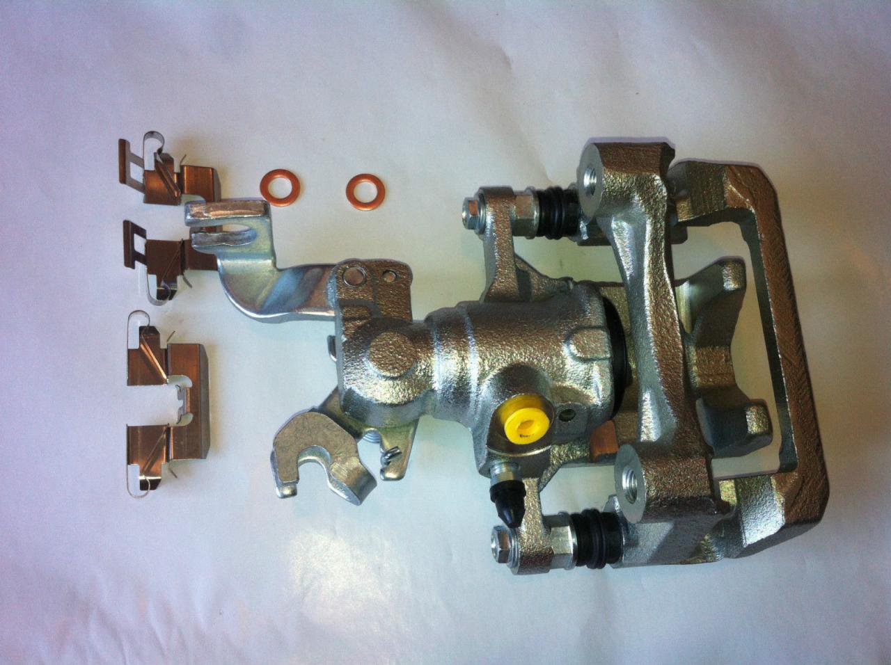 Zestaw naprawczy zacisku hamulcowego w Józefowie. Widoczne klocki, uszczelki i sam zacisk, gotowy do montażu. Precyzyjna naprawa i wymiana elementów układu hamulcowego.