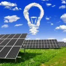 Rząd paneli słonecznych na zielonym wzgórzu pod błękitnym niebem z chmurą w kształcie żarówki, symbolizującą czystą energię.