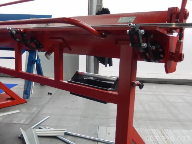 Czerwona zaginarka do blachy z oprzyrządowaniem, widoczne elementy regulacyjne i fragmenty profili blaszanych na podłodze.