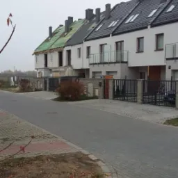 Szeregówka w trakcie budowy, z widocznymi etapami prac na poszczególnych segmentach, od surowego stanu po ukończony z oknami dachowymi i balkonami.