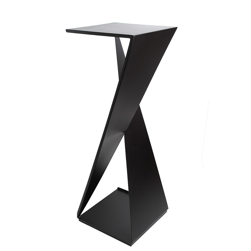 Czarny, metalowy stolik o geometrycznej konstrukcji z blatem w kształcie kwadratu i podstawą w kształcie ostrosłupa, połączonymi skręconą, płaską, metalową nogą.