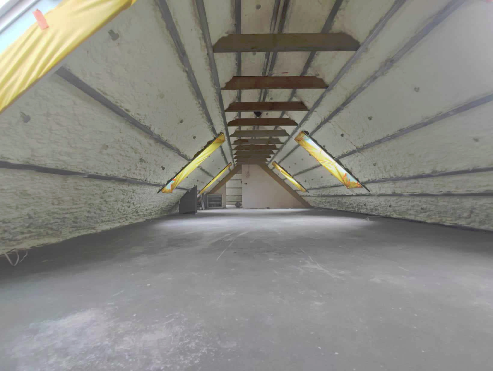 Poddasze po natrysku pianki izolacyjnej, widoczne drewniane belki stropowe i folia ochronna na elementach konstrukcyjnych.