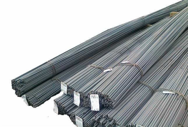 Stos wiązek stalowych prętów zbrojeniowych, związanych drutem i oznaczonych etykietami, ułożonych warstwami na białym tle. Widok z bliska.