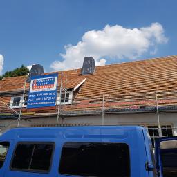 M&M BLACHARSTWO-DEKARSTWO MAREK MALISKA - Dom jednorodzinny w trakcie układania drewnianej konstrukcji pod pokrycie dachowe, widoczne rusztowania i reklama firmy dekarskiej, na pierwszym planie niebieski samochód dostawczy.