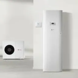 Biała, nowoczesna pompa ciepła typu split, składająca się z jednostki wewnętrznej i zewnętrznej, zainstalowana przy białej ścianie w minimalistycznym wnętrzu.