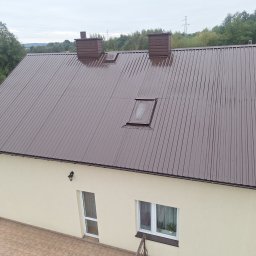 PHU Pro-Clean - Dom jednorodzinny z brązowym dachem z blachy trapezowej, dwoma kominami i oknem dachowym, widok z góry.